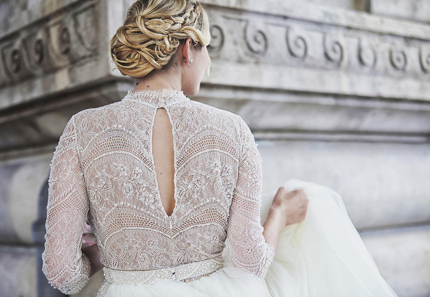 The back of a lace wedding dress against carved stone in Paris