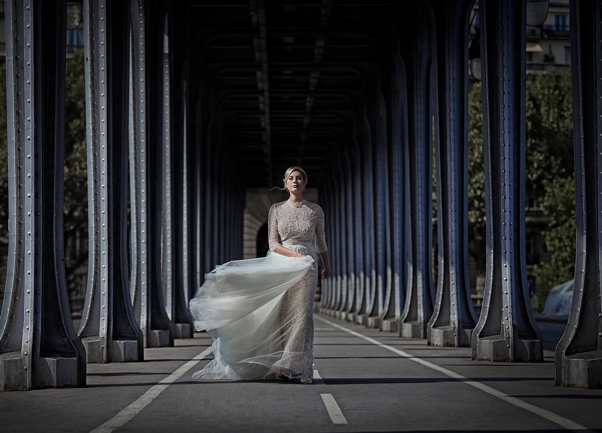A bride walking beneath the steel arches of the Pont de Bir-Hakeim in Paris
