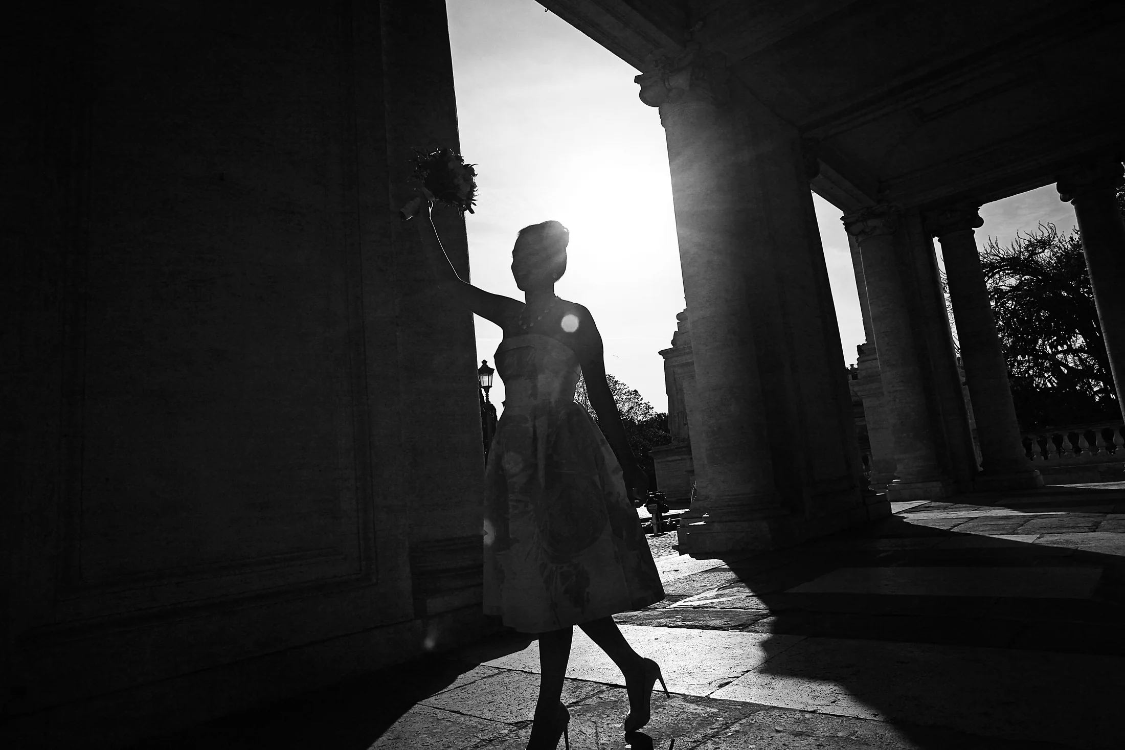 A bridal silhouette crossing between monumental columns