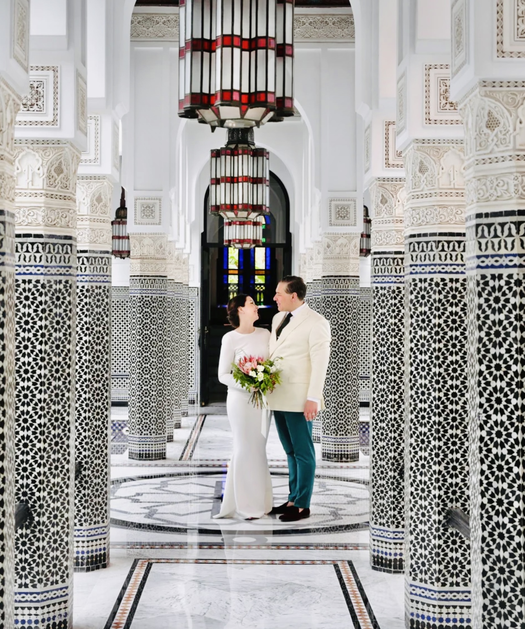 A newlywed couple framed by a tiled Moroccan courtyard