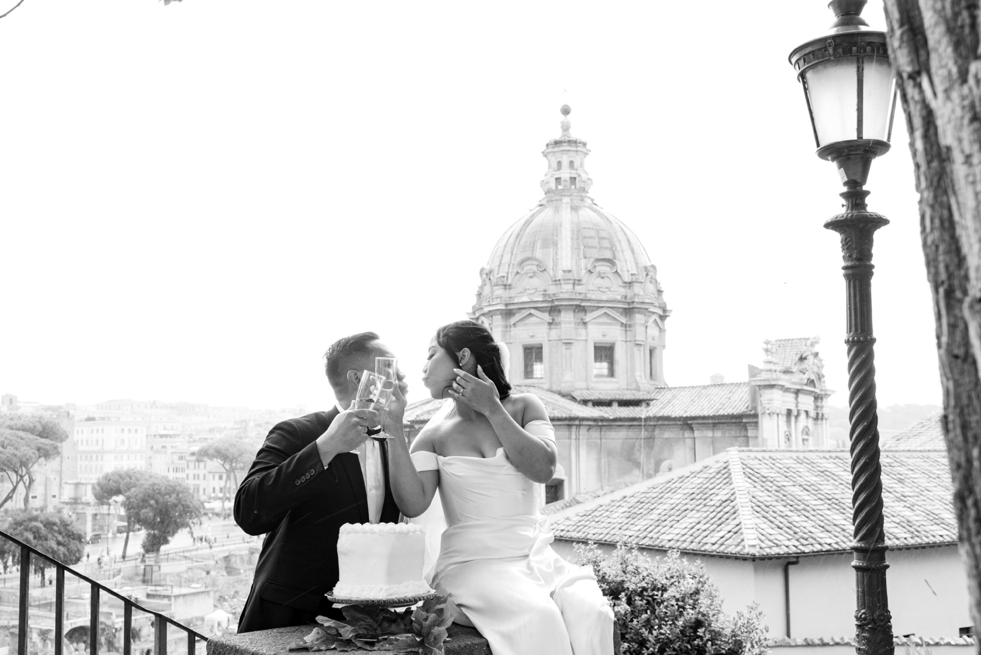 A newlywed couple toasting on a terrace above the Roman Forum