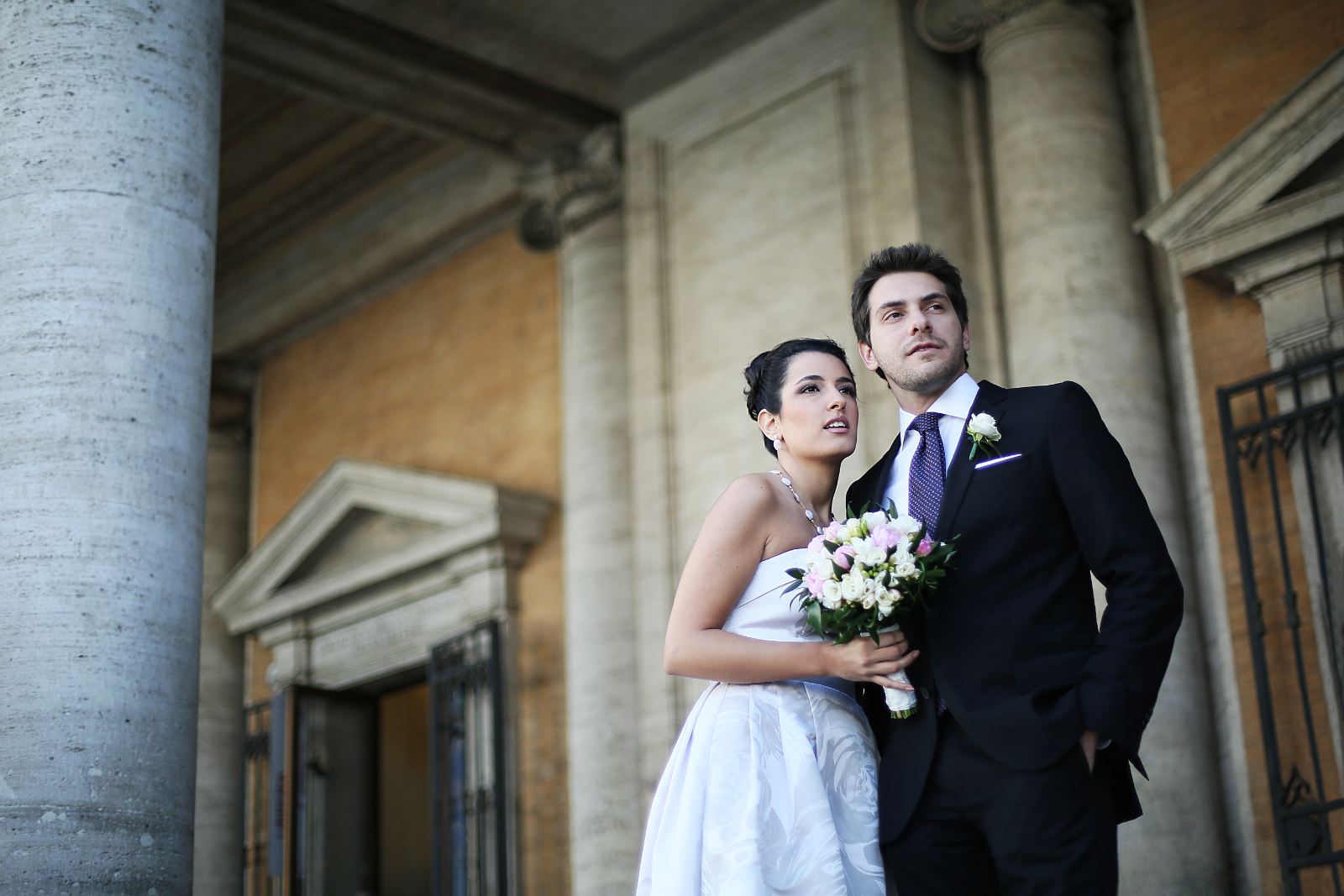 A couple kissing between monumental Roman columns