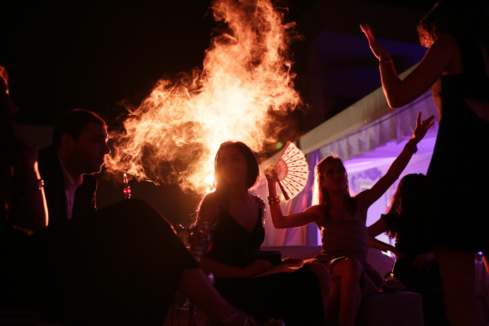 A couple pouring champagne beside fireworks and candle smoke